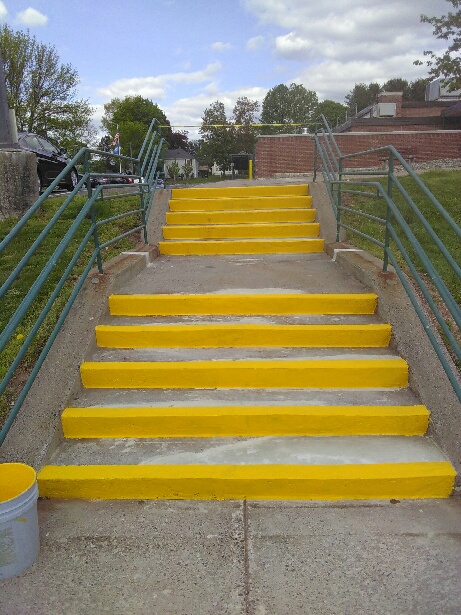 We Do Lines - A yellow painted stairway with metal railings.