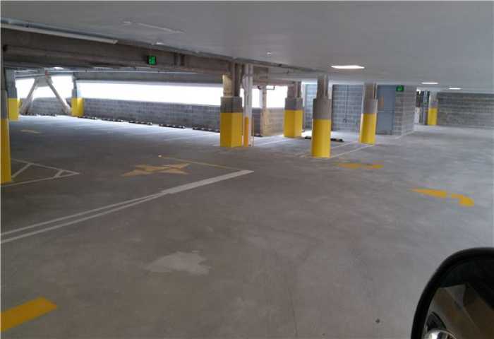 We Do Lines - A parking garage with yellow pillars and arrows on the floor to show the driving direction