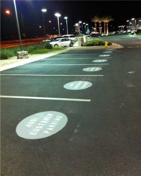 We Do Lines - A parking lot with signs painted on it at night.
