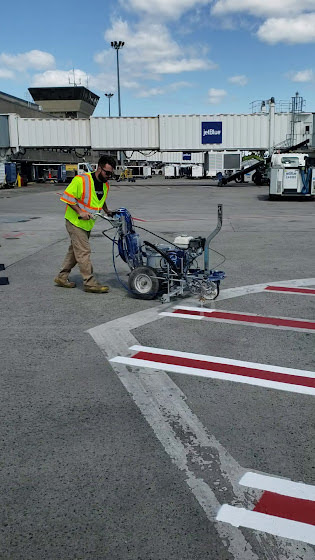 We Do Lines - A man is painting a runway at an airport.