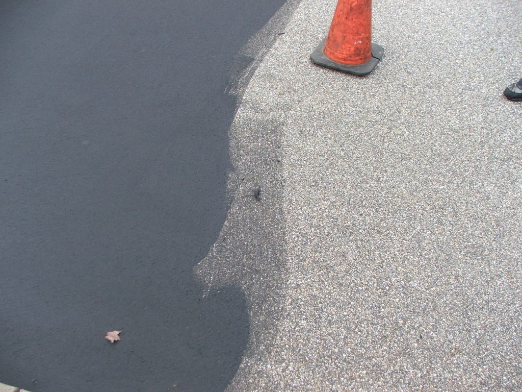 We Do Lines - An efficient solution for asphalt repair in a parking lot, seen in a black paved street with an orange cone in the middle.