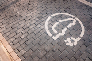 We Do Lines - An electric car charging station on a brick sidewalk.