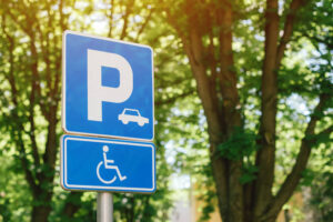 We Do Lines - A parking sign with a wheelchair and trees in the background.