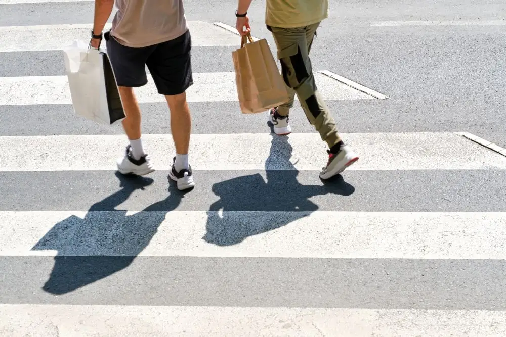 Photo of two persons walking across a zebra crossing showing only their lower bodies.